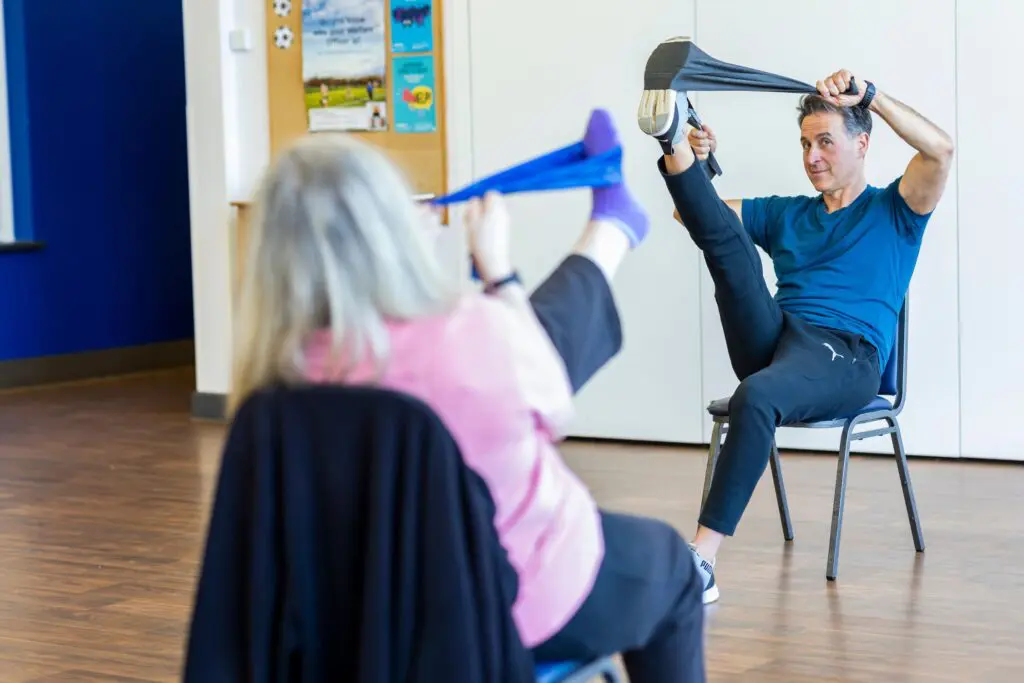 A fitness trainer conducting an exercise class for elderly people as part of the care home activities