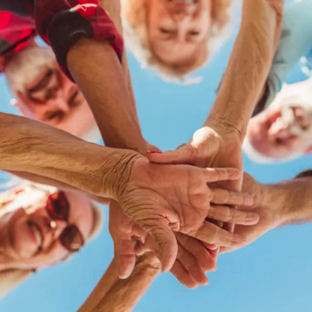 Care residents joining hands in a circle